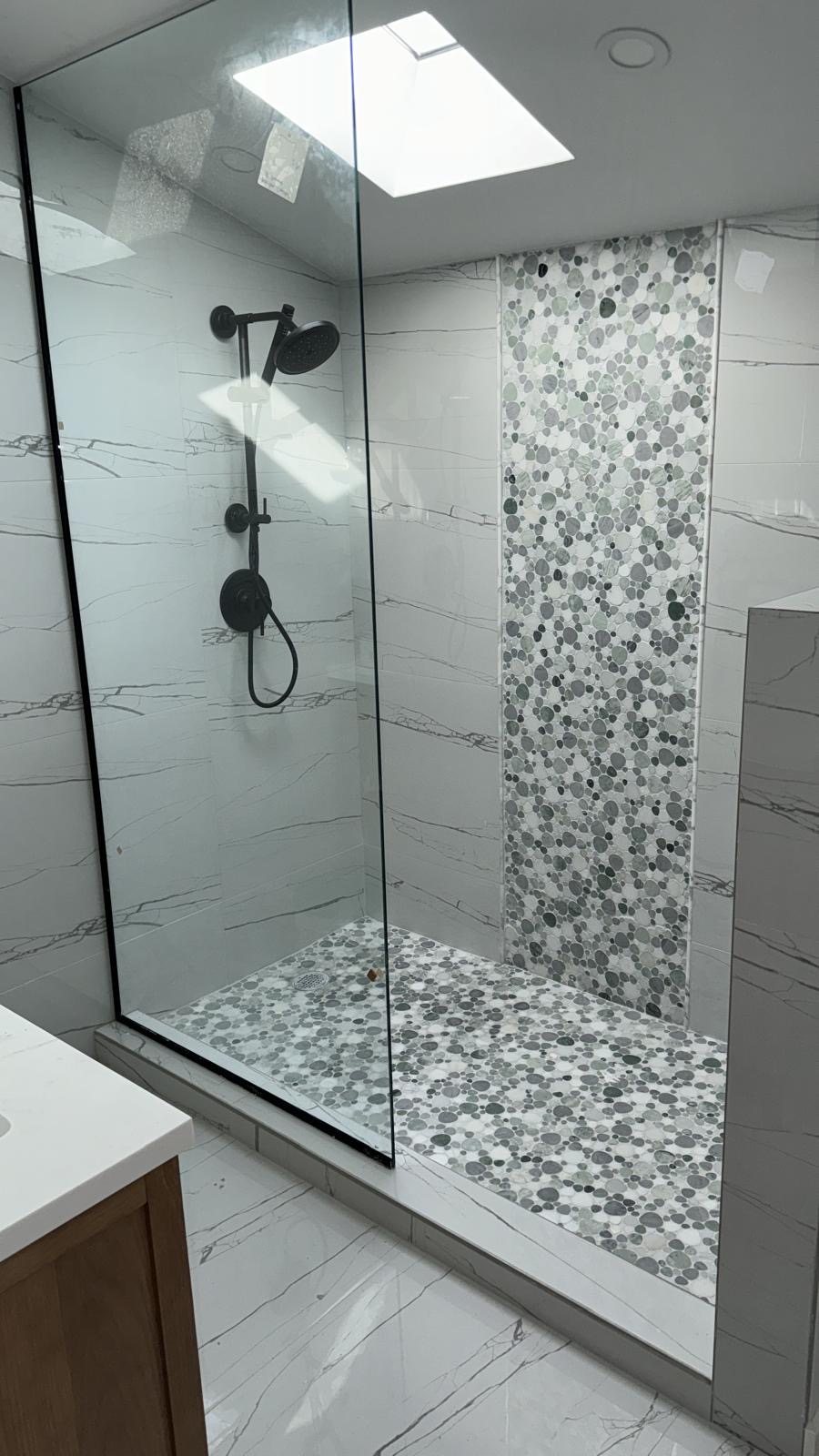 Finished bathroom with marble tile walls and pebble mosaic shower floor.