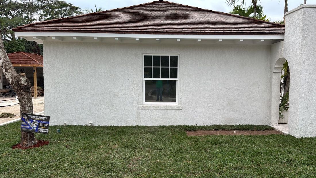 Freshly painted white stucco home with cedar shake hip roof.