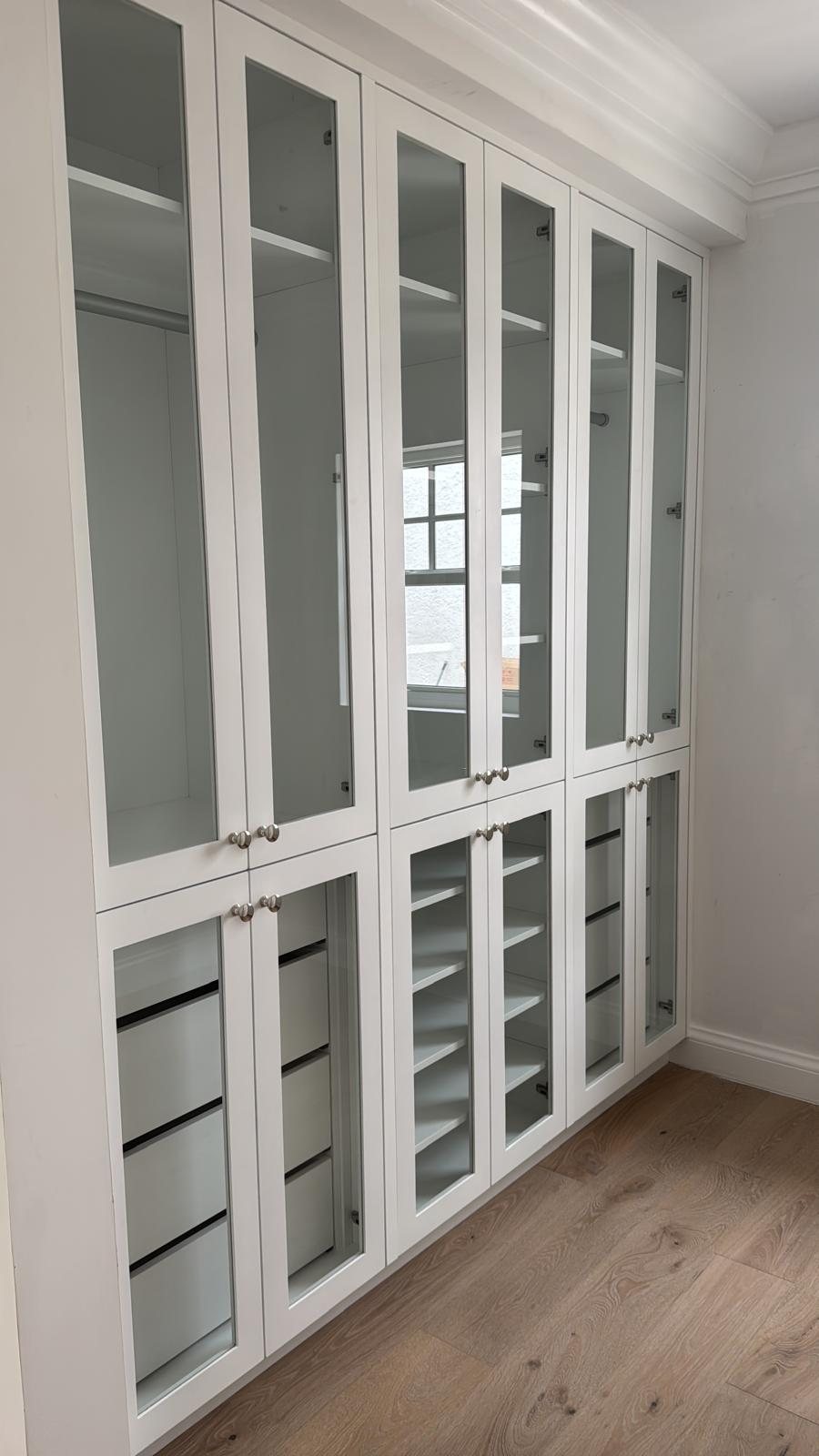 Built in wardrobe with glazed doors, internal shelving and drawers, finished in white.