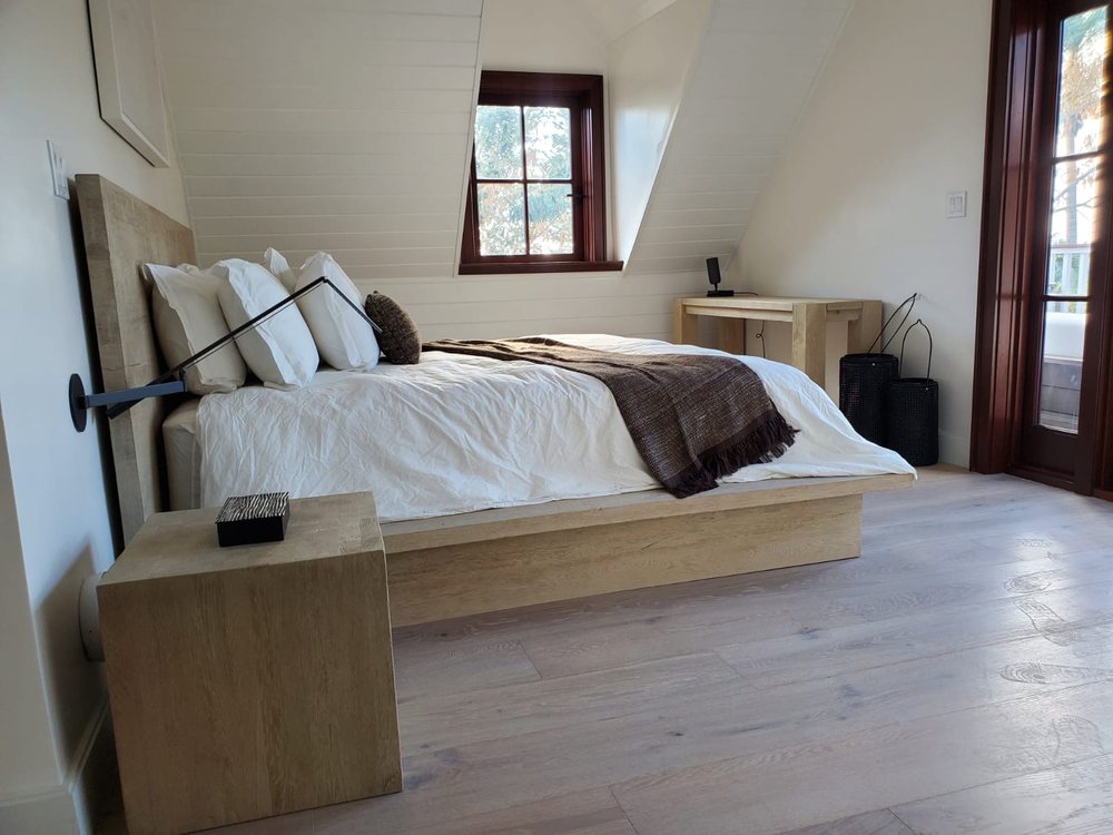 Upstairs bedroom under a vaulted ceiling with wide plank flooring.