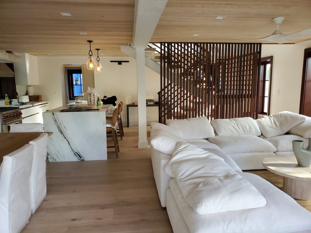 Open kitchen and living area with timber ceiling and slatted stair screen.