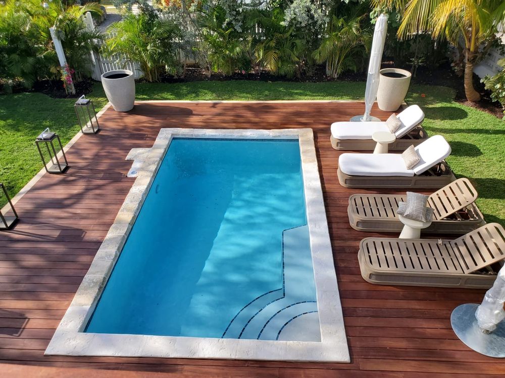 Pool set into hardwood decking seen from above with loungers alongside.
