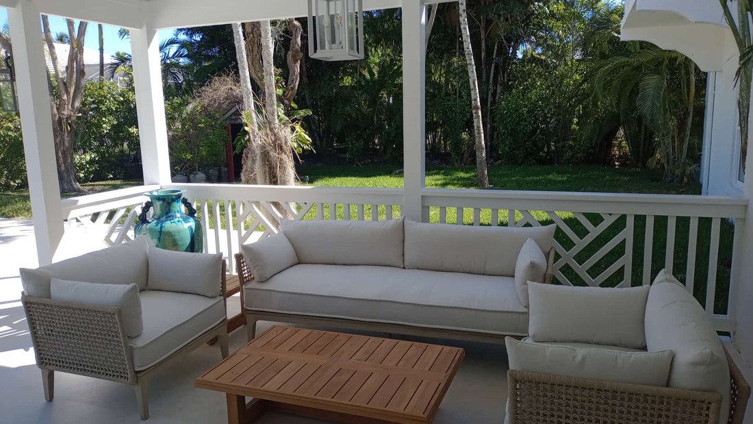 Covered porch with chippendale railing and white upholstered seating.