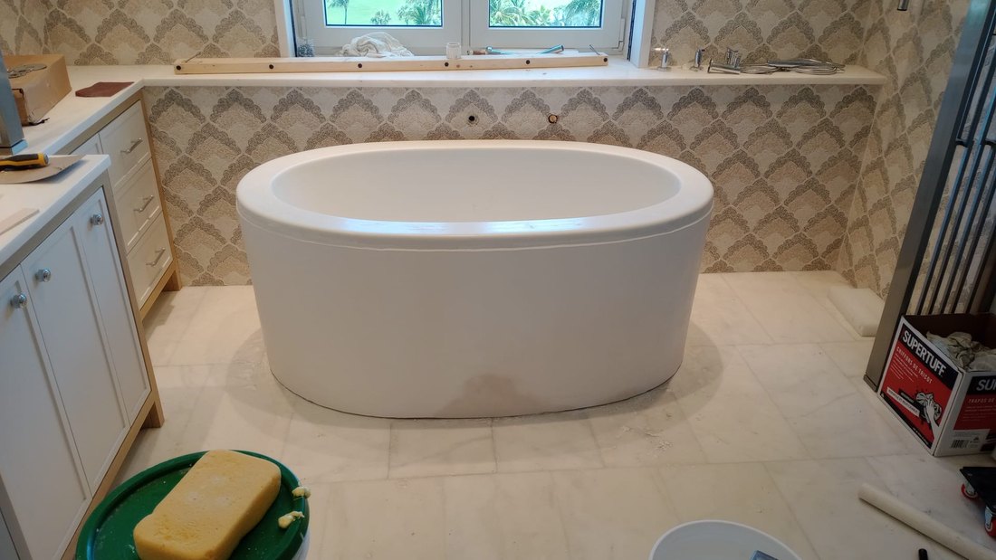 Freestanding bath set against patterned tile with the marble floor going down.