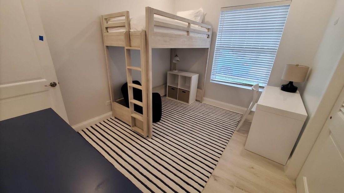 Bunk room with a timber loft bed, desk and wide plank flooring.