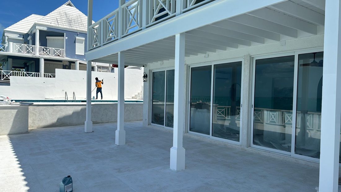 Covered terrace with white columns and sliding doors opening onto the pool and the water.