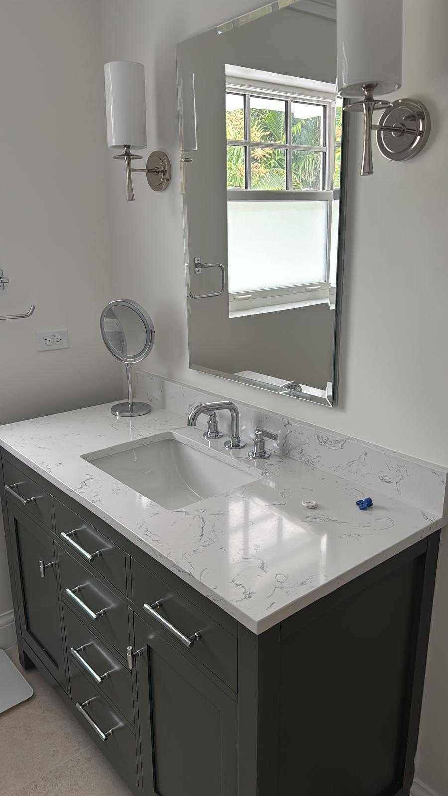 Bathroom vanity in dark timber with a marble top and polished nickel fittings.