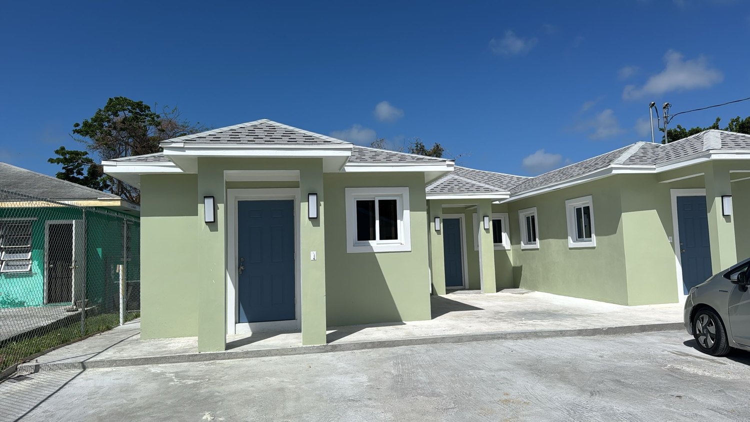 Newly completed apartment units on Cow Pen Road in pale green stucco with blue doors and shingle roofs.