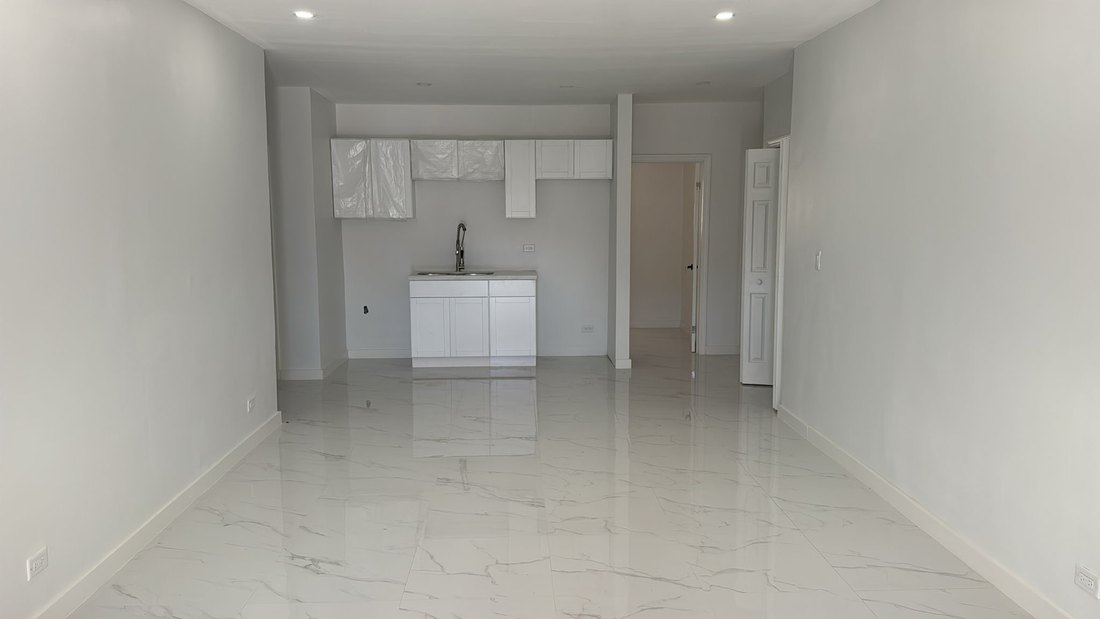 Open plan living and kitchen area with polished marble effect floor tiling.
