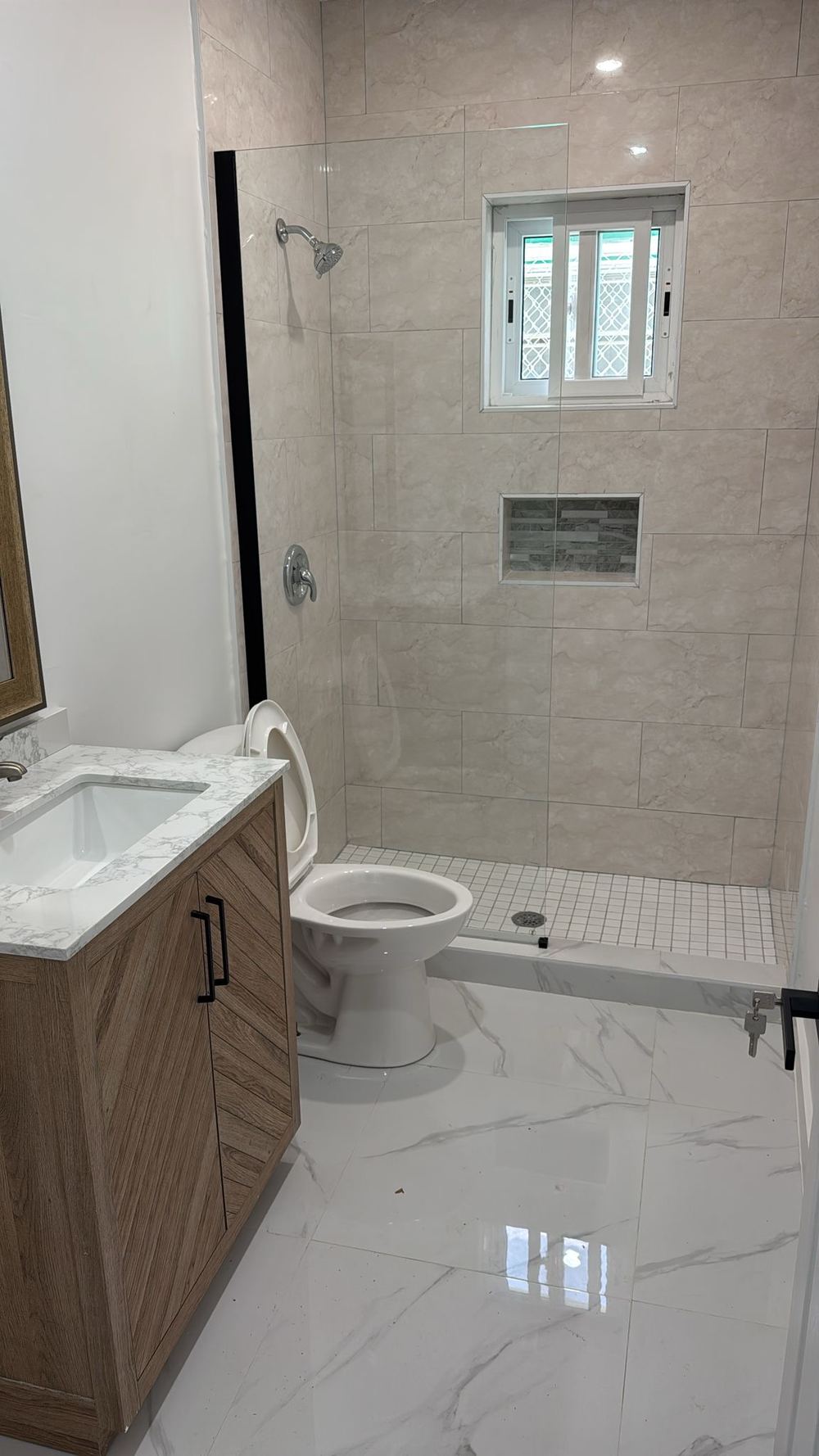 Bathroom with tiled shower, glass screen, timber vanity and stone top.