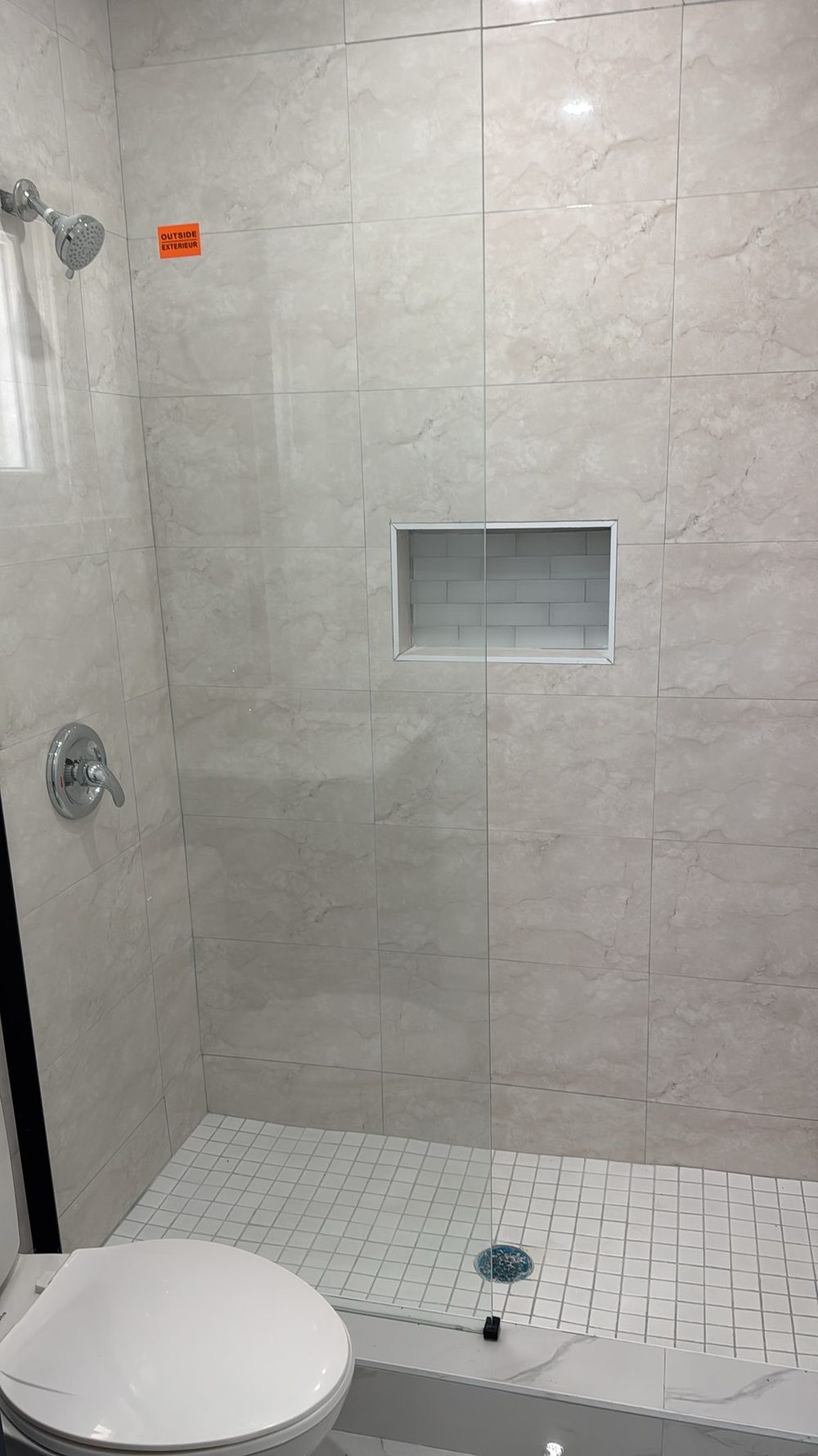 Tiled shower with a recessed niche and mosaic floor.