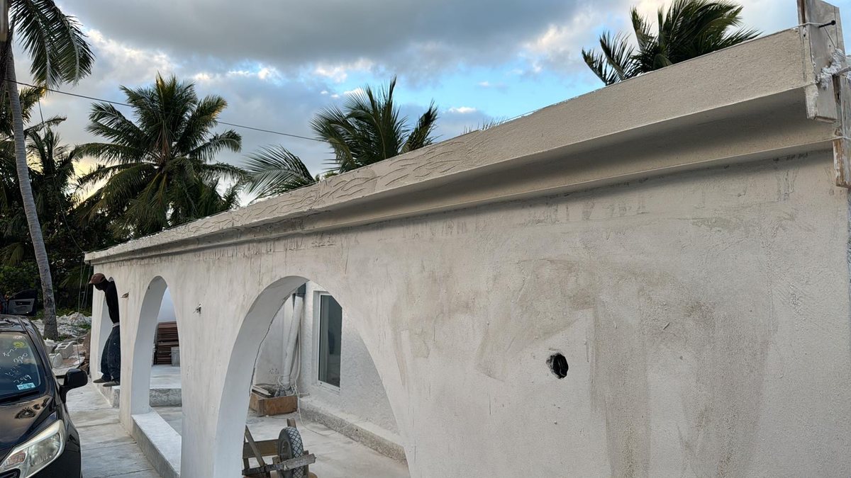 Plastered archways and roof edge on a home nearing completion at dusk.