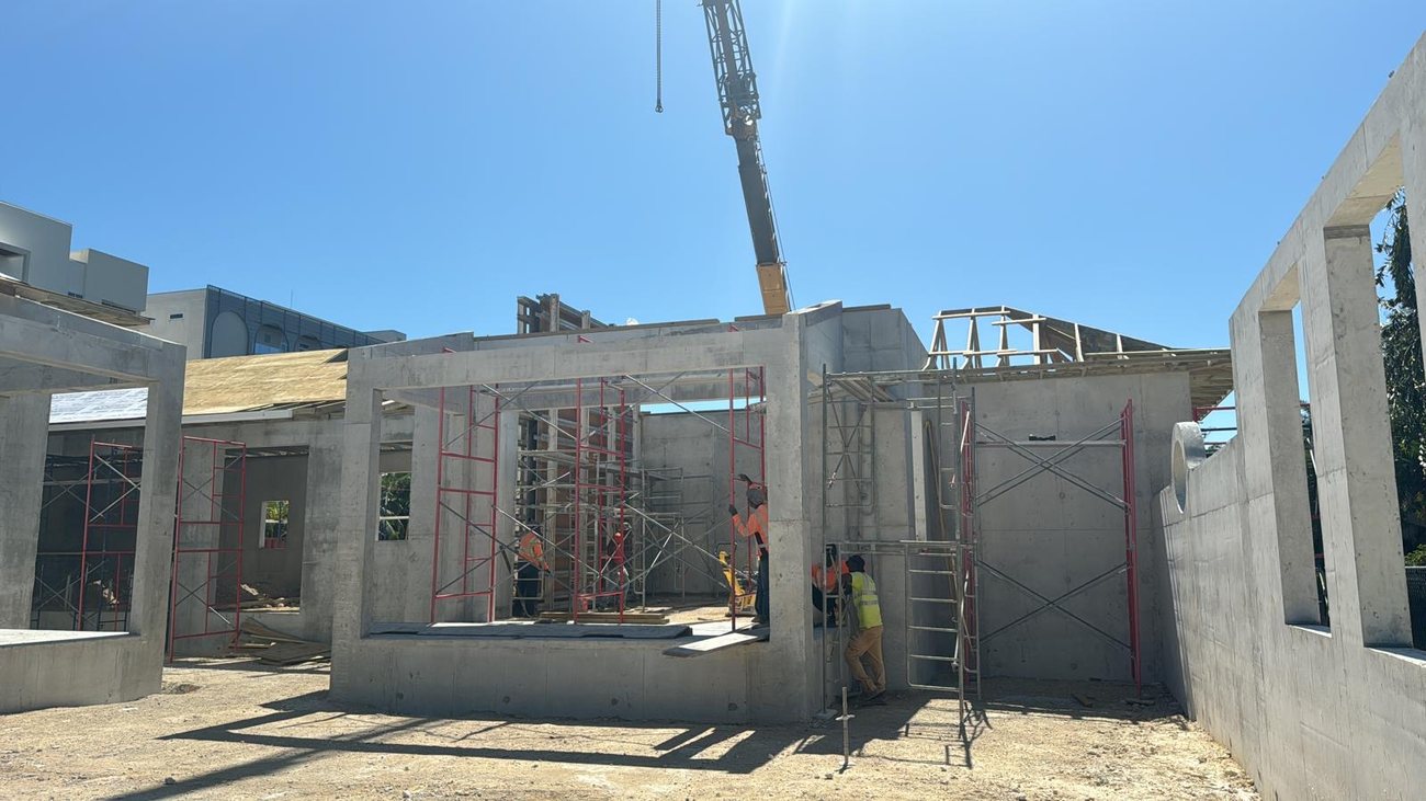 Crane and a hi vis crew working a multi unit concrete site.
